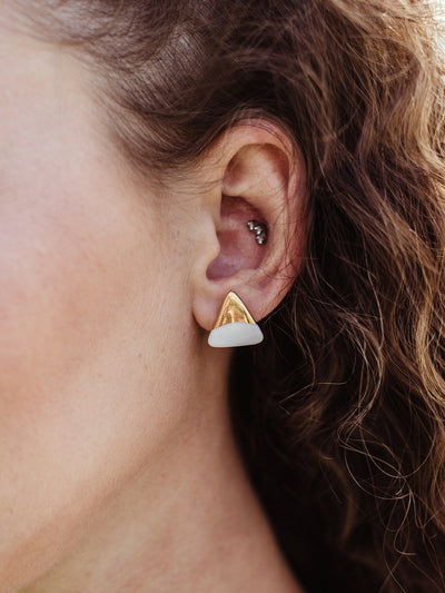 Closeup of white female wearing triune studs.