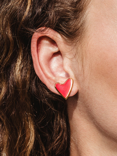 Close up of red heart studs on white female model.