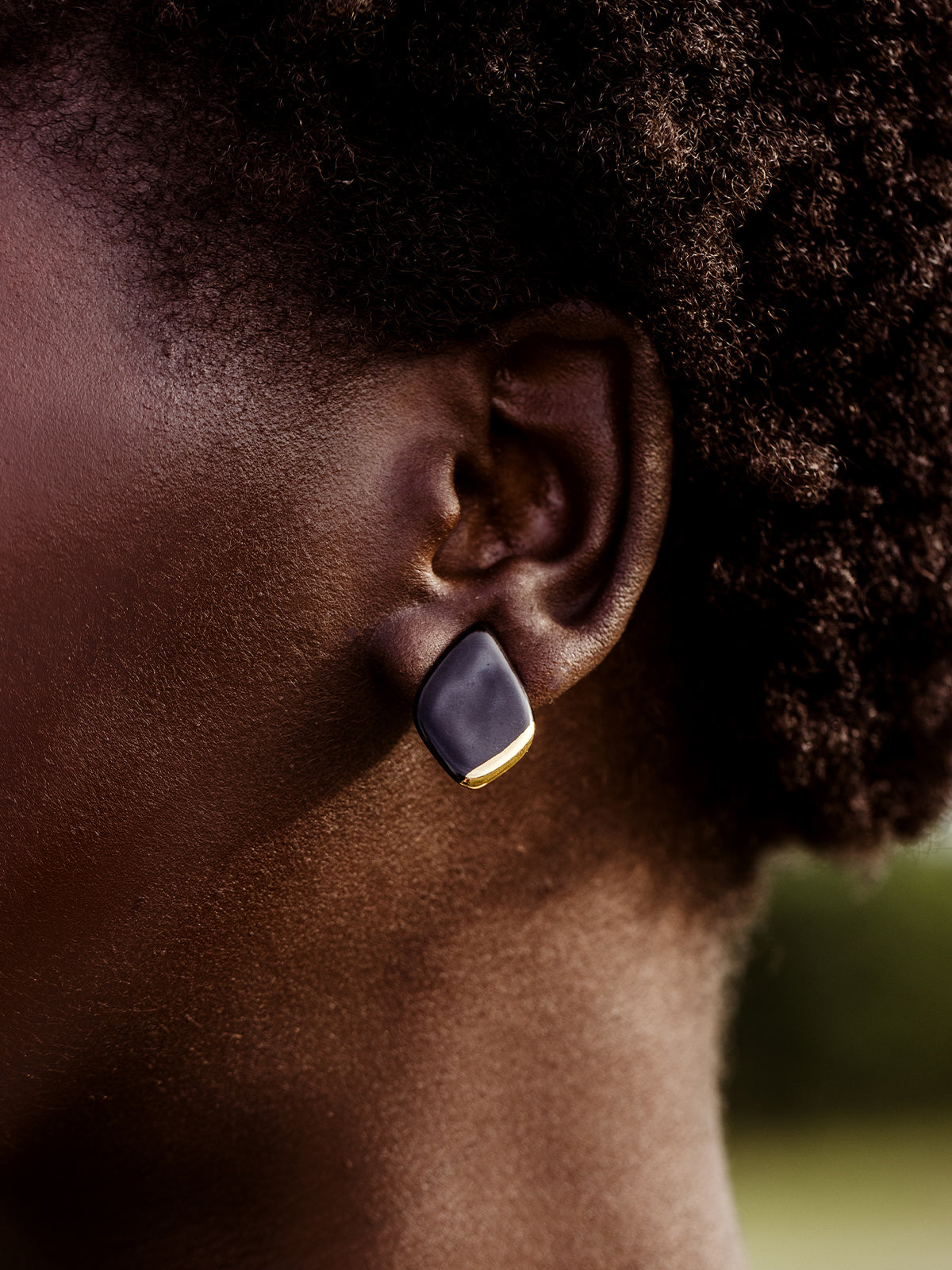 Close up of porcelain diamond stud earrings on African female model. 