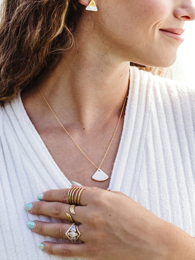 Closeup of white female model wearing the fan pendant necklace. 