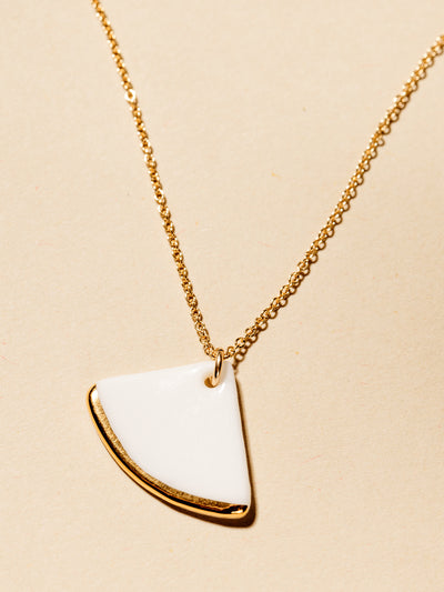 White fan necklace with gold dipped edge on cream background.