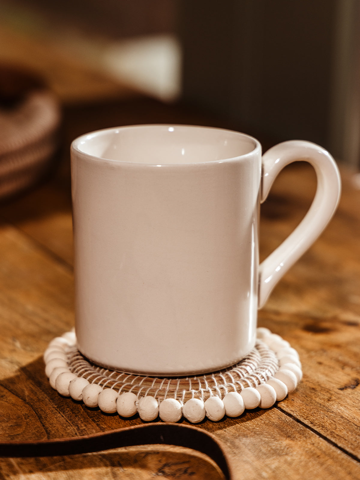 Beaded coaster with mug placed on coaster while sitting on wood surface