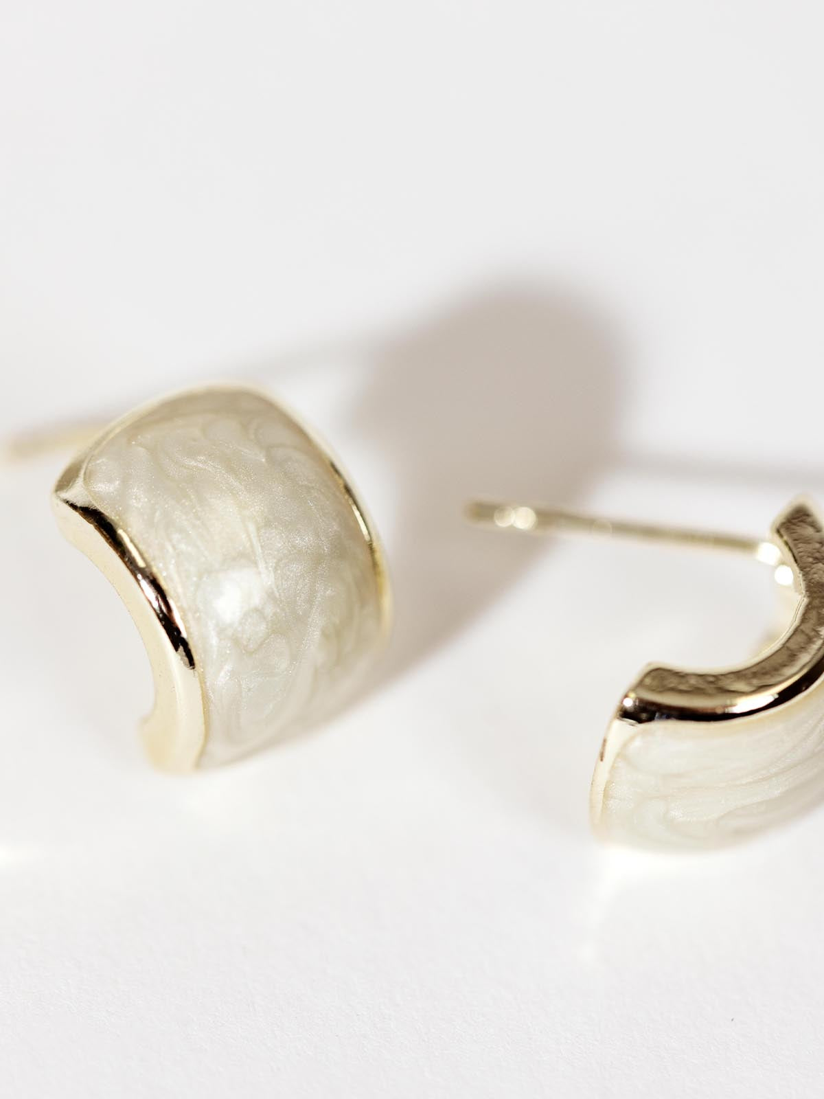 Ivory half hoop style earrings white background.