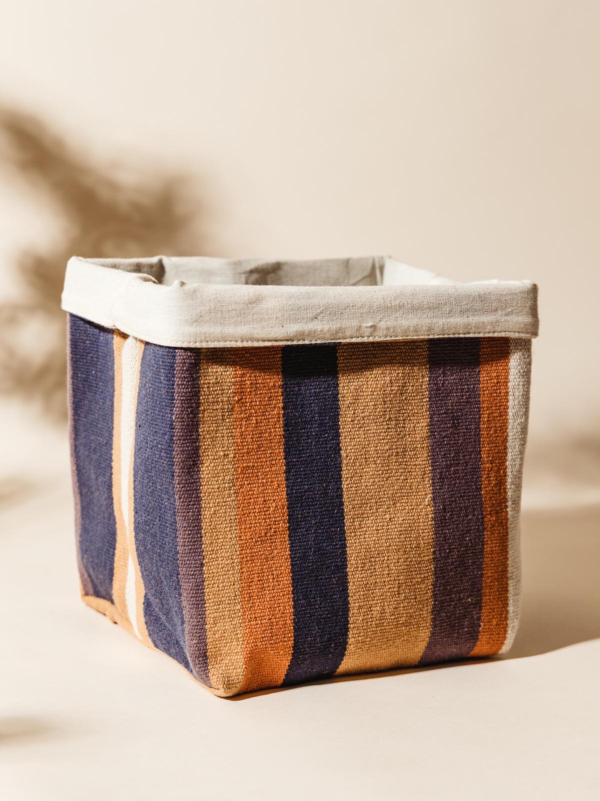 Large Handcrafted fabric storage basket with bold orange, navy, and beige stripes, showcasing its spacious interior and sturdy design.