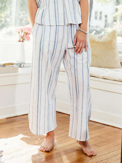 Close-up of a woman's hand resting on the pocket of wide-legged striped lounge pants from Swahlee. Sustainable sleepwear made for comfort.