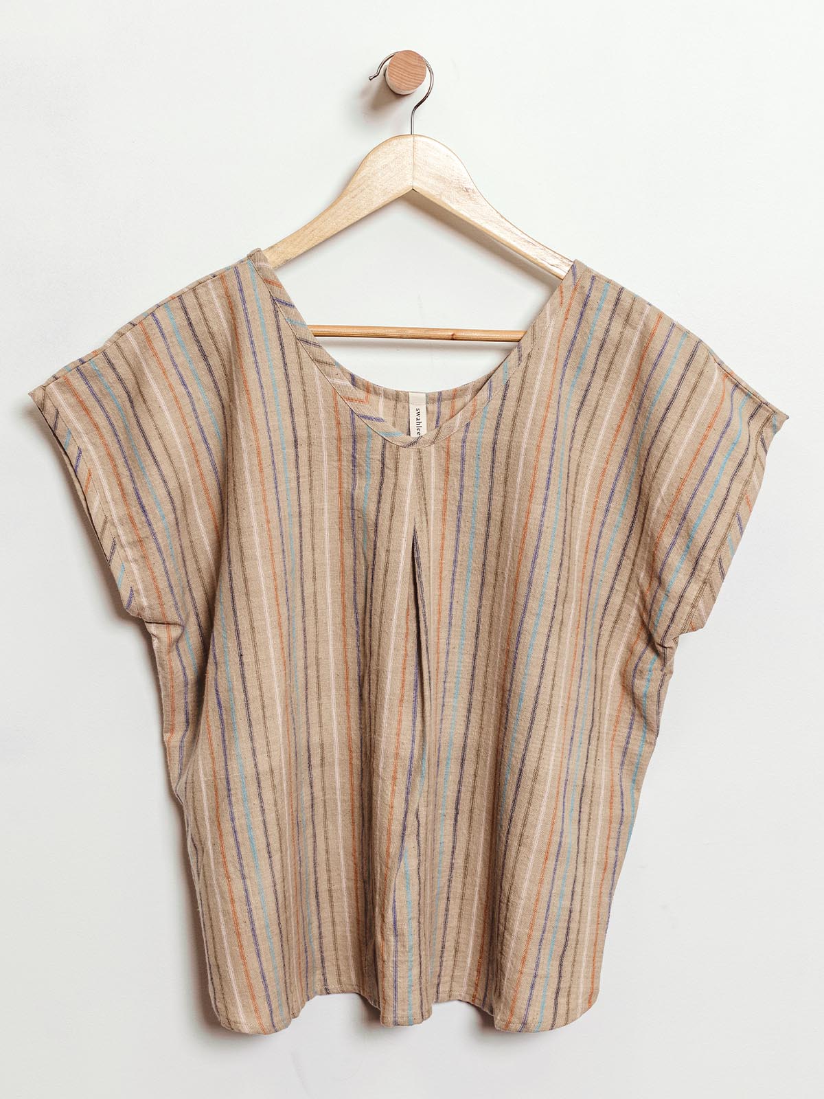 Sustainable short-sleeve top with multicolored vertical stripes in earthy tones, displayed on a wooden hanger. This ethically made, loose-fit shirt features a v-neckline and a central pleat, offering a relaxed yet stylish look for everyday wear.