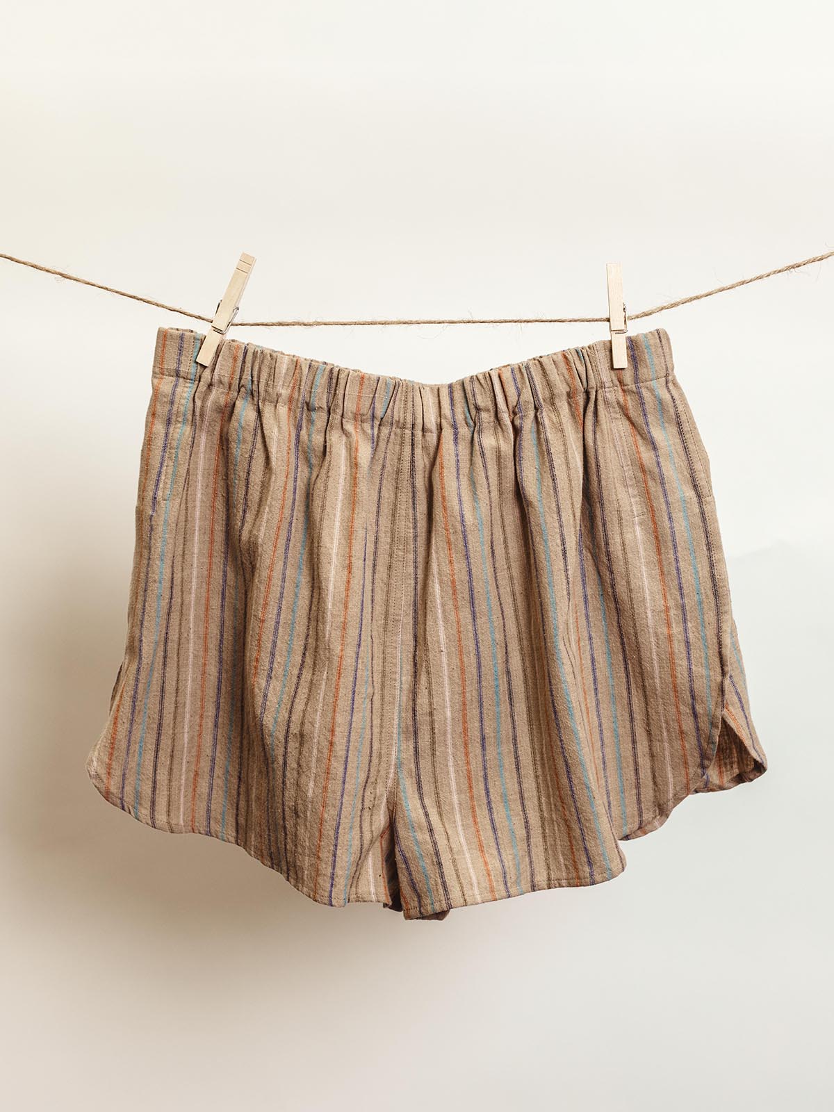 Handcrafted lounge shorts in brown with multicolored vertical stripes, designed with an elastic waistband and relaxed fit. Ethically made from sustainable materials, these shorts offer comfort and style for casual or lounge wear.