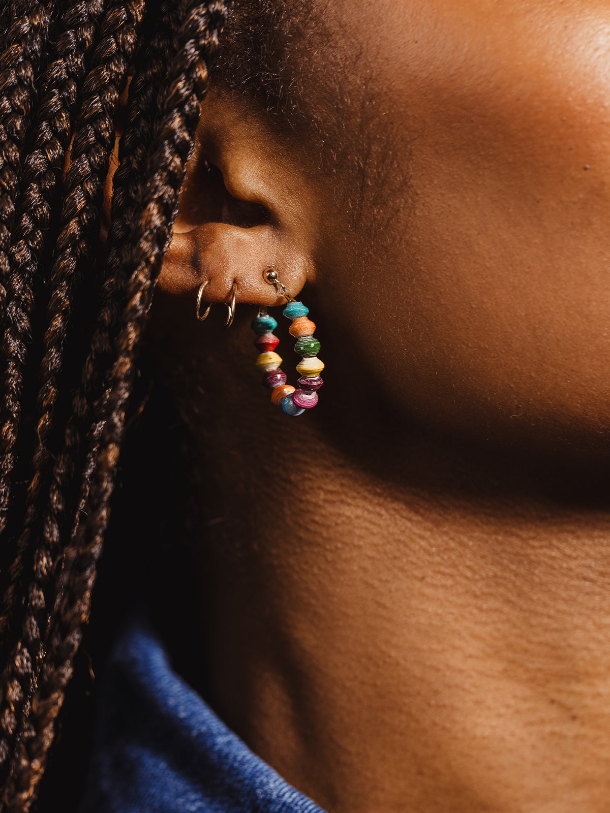 Detailed view of a gold hoop earring adorned with multicolored recycled paper beads, highlighting eco-friendly and ethically made handcrafted jewelry.