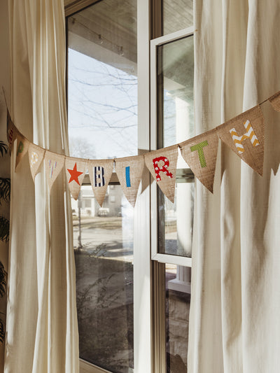 A close-up view of a handcrafted burlap birthday banner with patterned fabric letters, perfect for a sustainable and reusable party decoration.