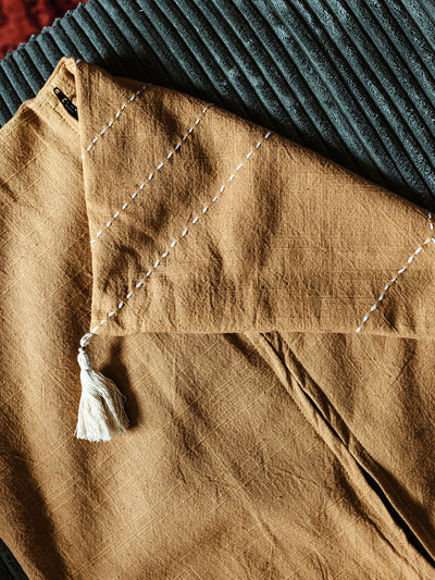 Closeup of yellow/mustard pillow cover fabric on plush olive green couch. 