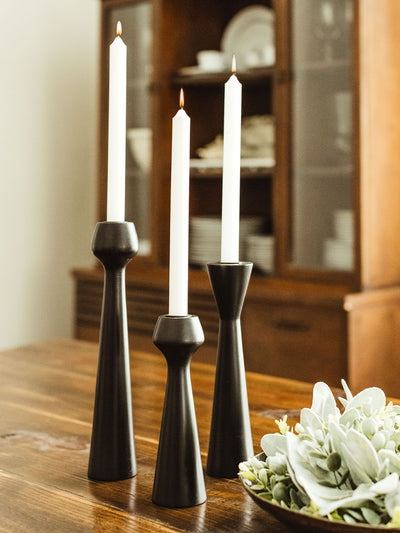 Black wooden candle stand set on dinning room table. 