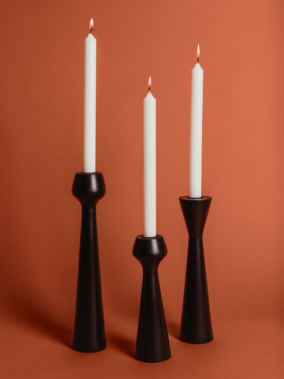 Black wooden candle stand set on rustic orange studio background