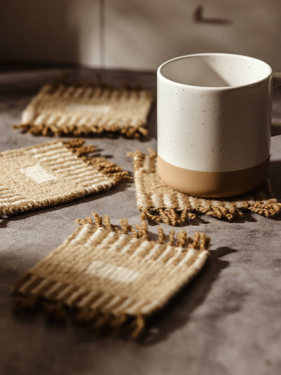 Close-up of a handwoven coaster under a ceramic mug, capturing the intricate weaving and warm color palette.