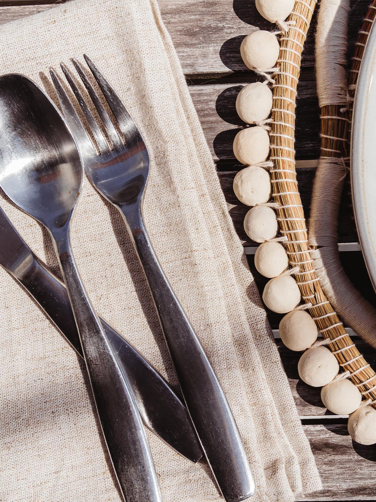 silverware on cream cloth napkins at outdoor table setting.